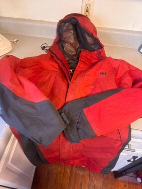 Experience warmth with Helly Hansen's vibrant red and charcoal jacket. Ideal for